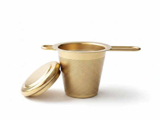 Wandering Leaf Co gold fine-mesh tea infuser with a matching lid that doubles as a coaster on a white background
